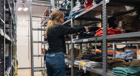 Worker putting away clothes in back of house retail