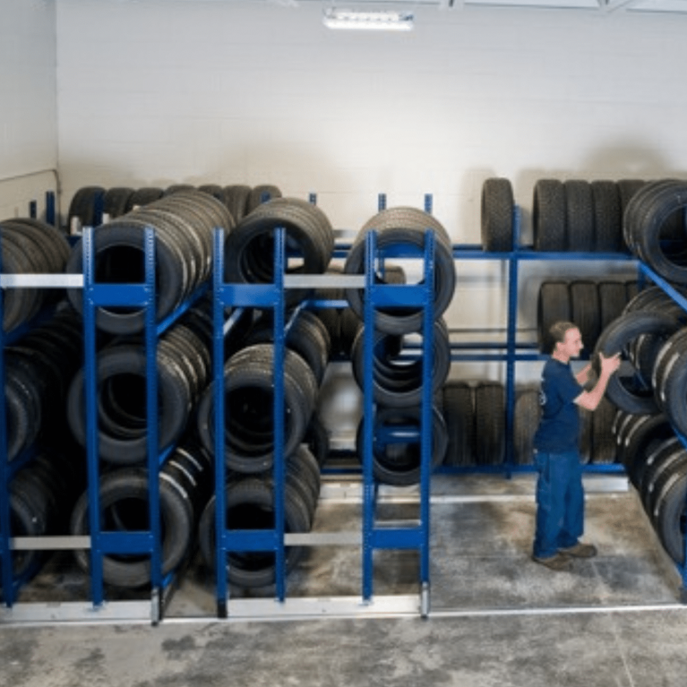storage racks holding tires with a man standing between racks